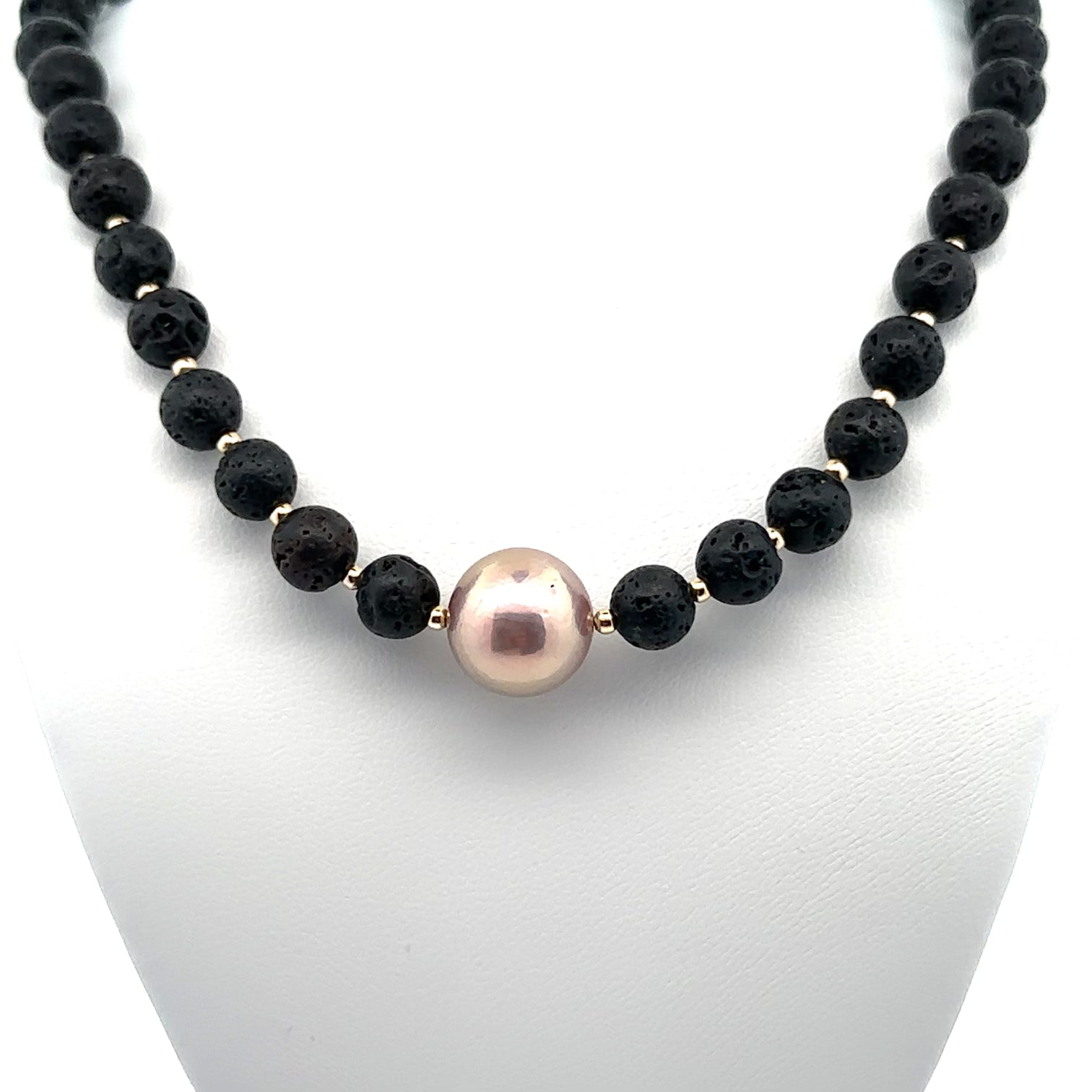 Close-up of the Kaia Lava Rock necklace highlighting the central dark Black Tahitian pearl framed by natural black lava stone beads with gold spacers.