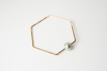 Front view of The Lōkahi gold-filled geometric bangle bracelet featuring a single light-toned or white Edison pearl on a white background.
