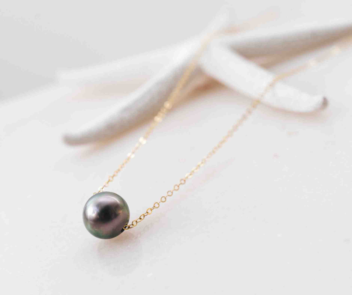 The Mo‘i Necklace featuring a single black  Tahitian pearl suspended on a delicate gold-filled chain.